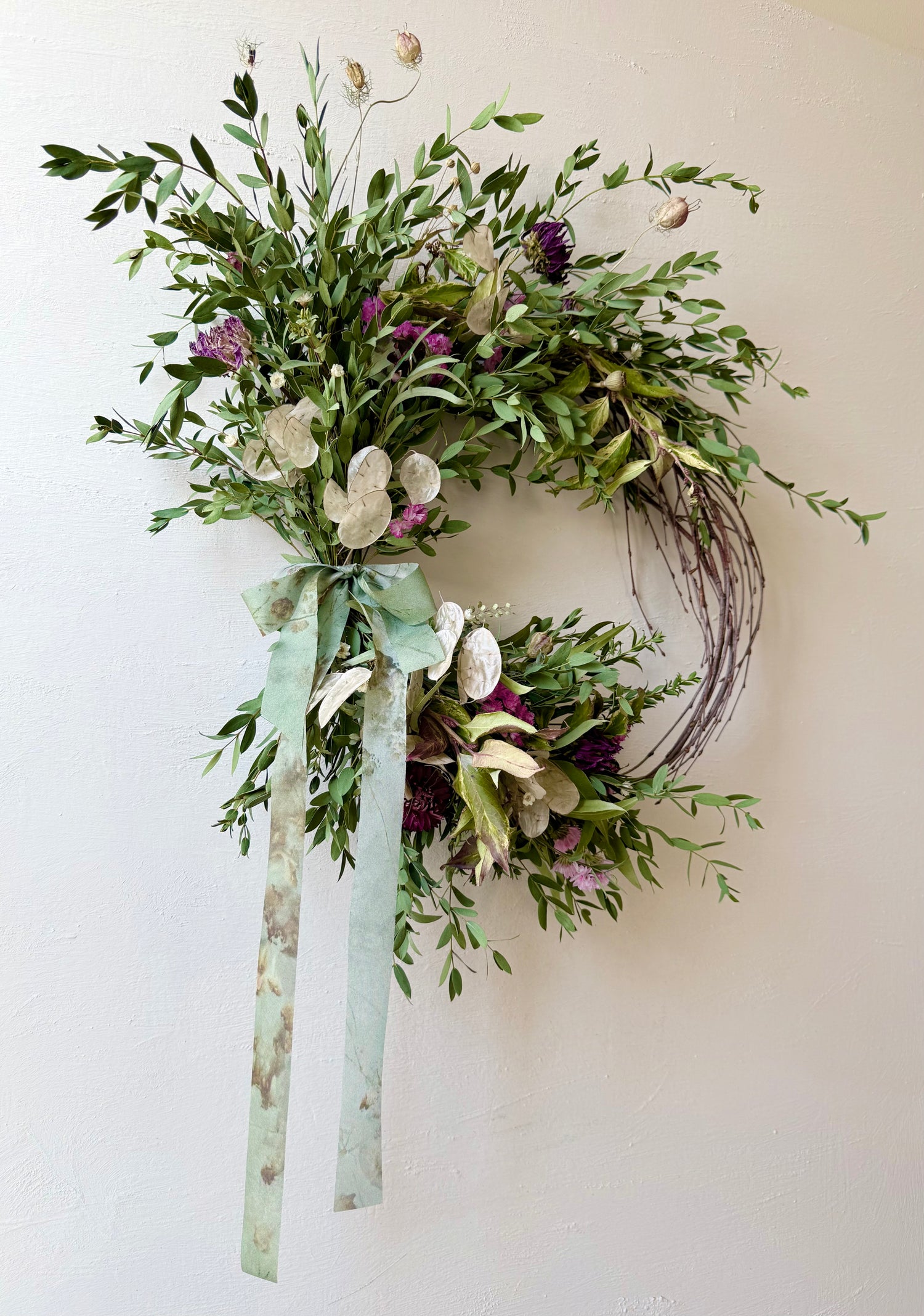 Handcrafted BETWIXT botanical wreath with dried dahlia, honesty, statice, eucalyptus, and natural grasses on a vine base in soft earthy tones.