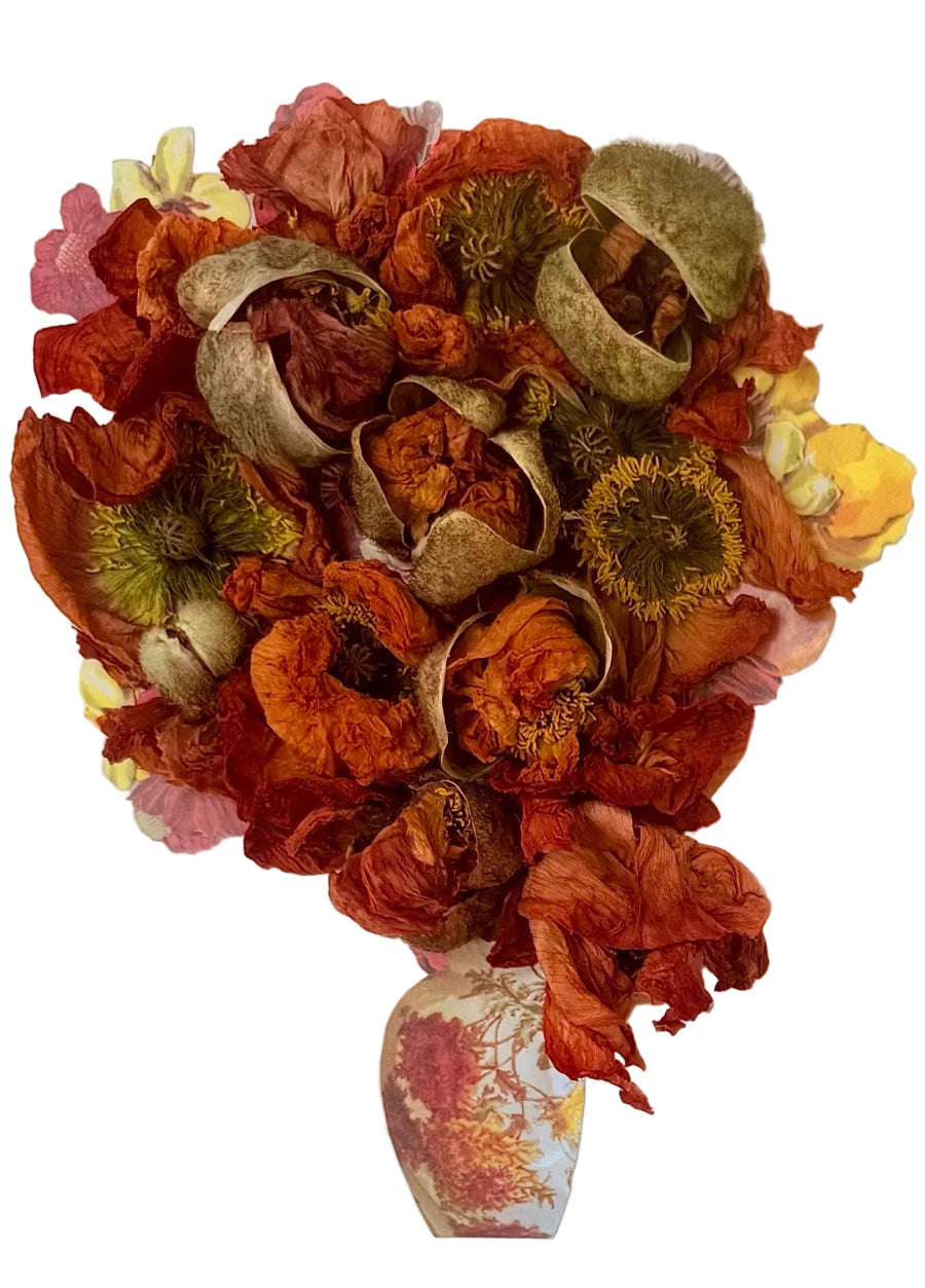 Handcrafted floral collage with dried poppies and paper elements juxtaposed with small vase.