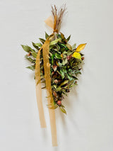 Handcrafted AWAKENING botanical swag with flowering Camellia, dried grasses, and natural foraged botanicals in warm earthy tones.