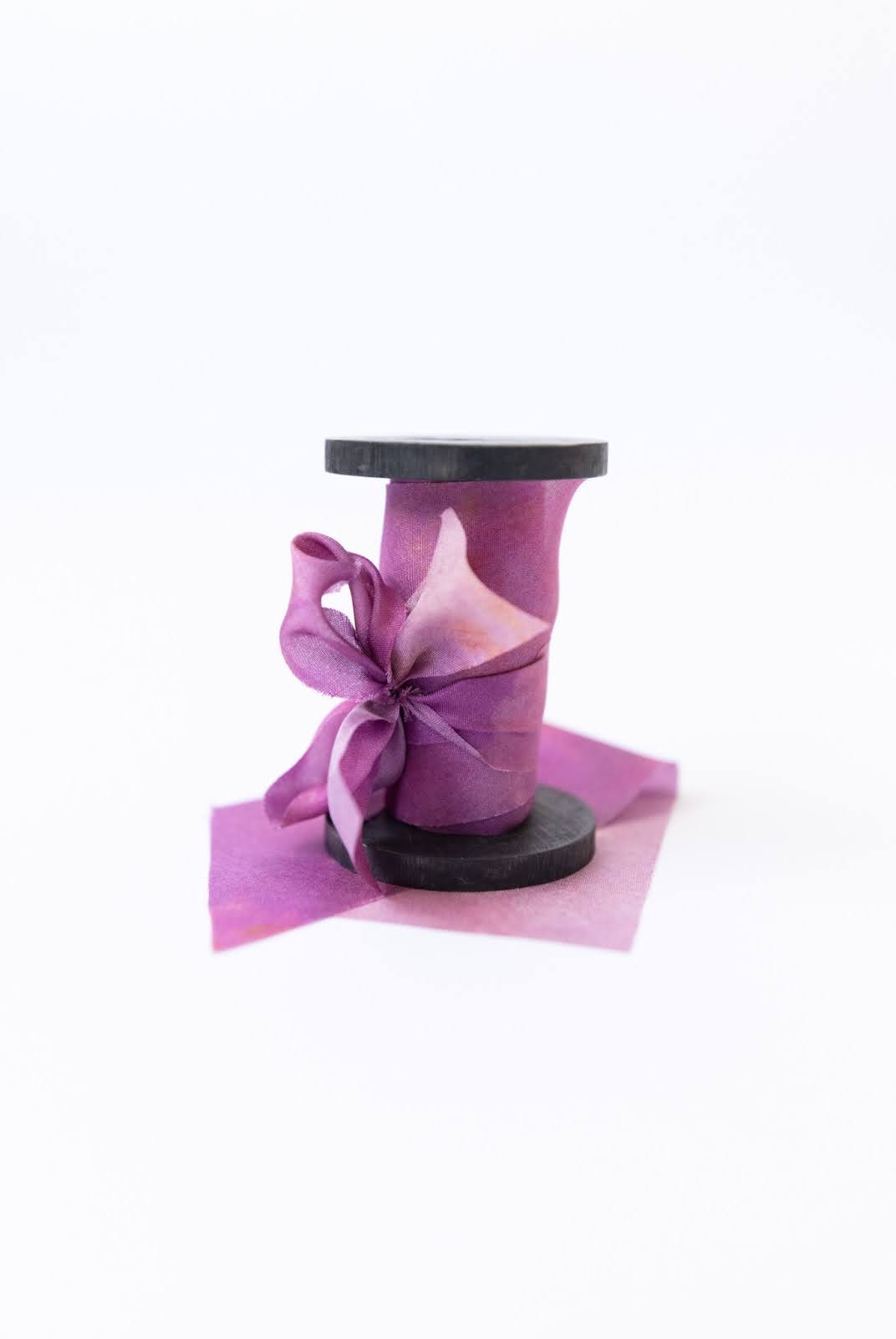 Botanical print silk ribbon in natural earthy tones displayed on FSC-certified wooden spools for wreath and floral styling.