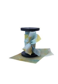 Botanical print silk ribbon in natural earthy tones displayed on FSC-certified wooden spools for wreath and floral styling.